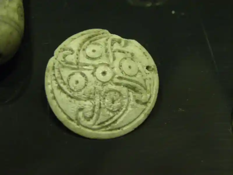 Ornament with a rounded swastika intersecting with a cross composed of circles design